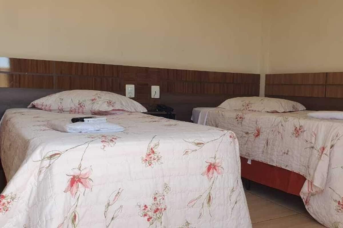Une chambre avec deux lits, chacun agrémenté de draps à motifs floraux et de têtes de lit en bois.