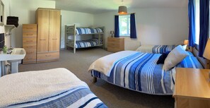Ein Schlafzimmer mit zwei Betten, einem Kleiderschrank, einem Schminktisch und einem Heizkörper. Ein Fenster mit Vorhängen.