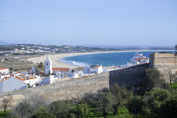 Un pueblo costero con edificios blancos, una playa y una fortificación.