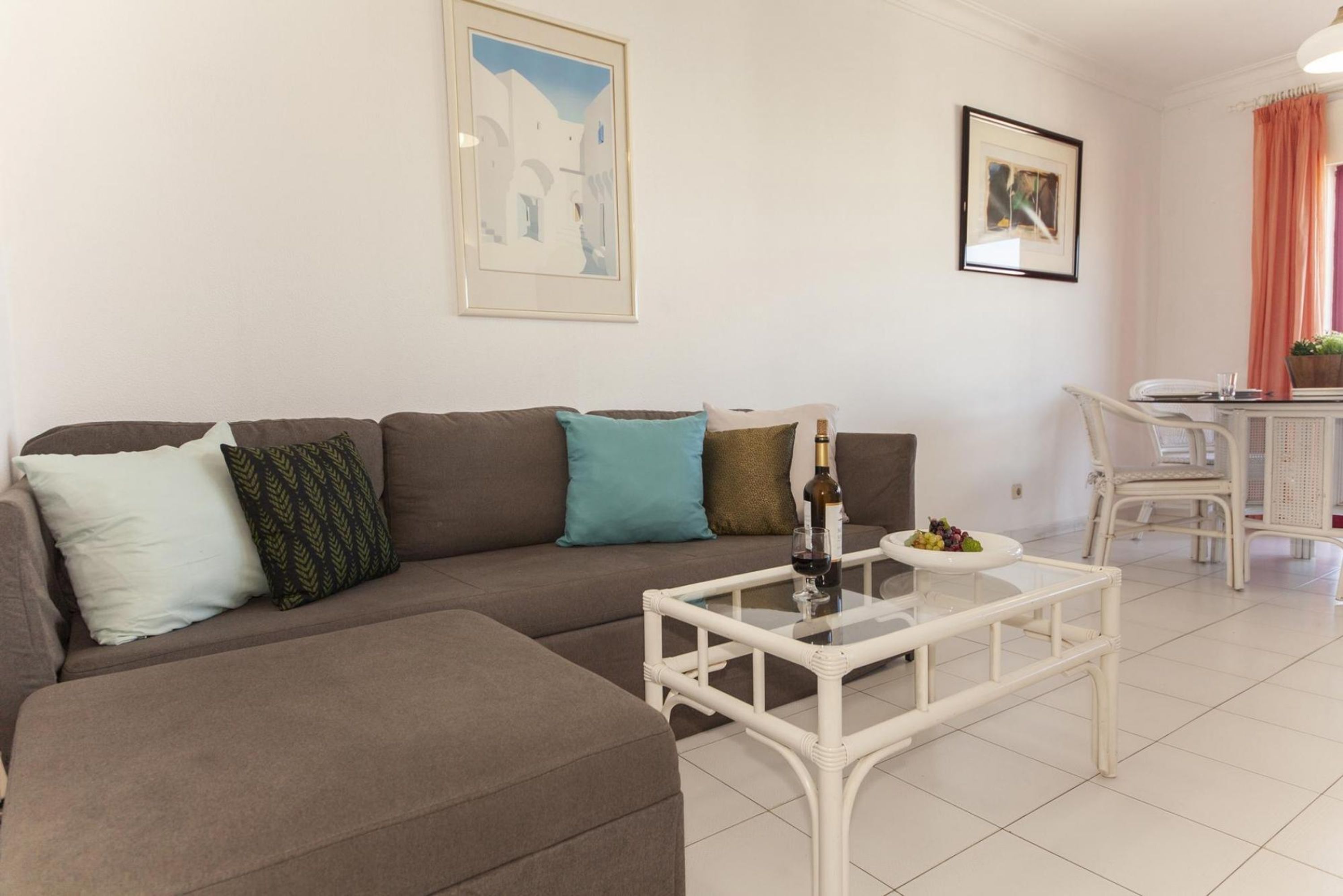 Ein Wohnzimmer mit einem braunen Sofa, einem Glastisch und einem weißen Sessel.