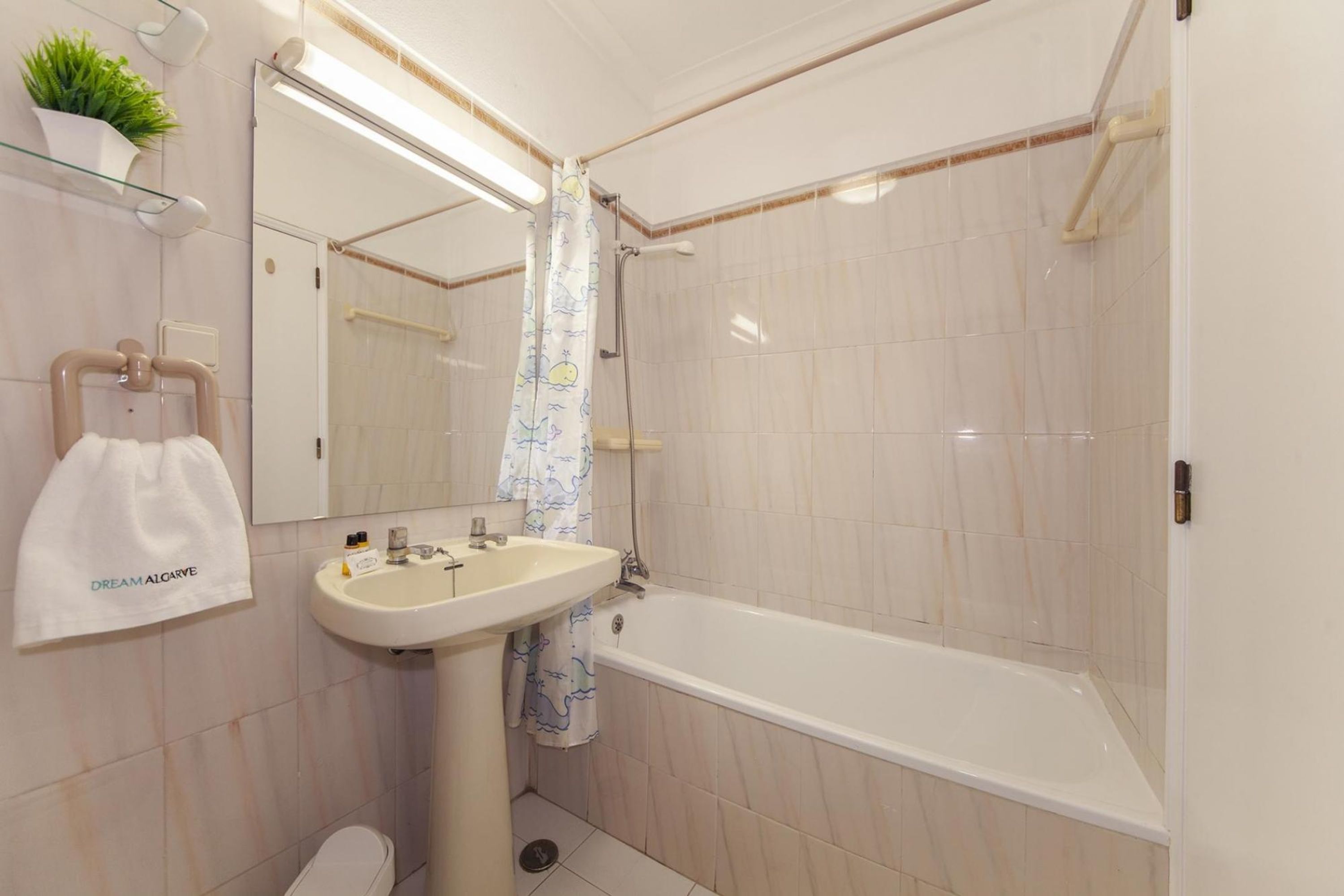 Een badkamer met een wit wastafelmeubel, een badkuip en een douchegordijn met een stripcartoonontwerp.
