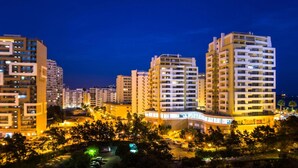 Un complejo hotelero de rascacielos con varios pisos, ventanas iluminadas y un área de estacionamiento bien iluminada.