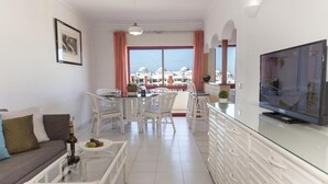 Una sala de estar moderna con sofá, mesa de comedor, sillas y televisor.