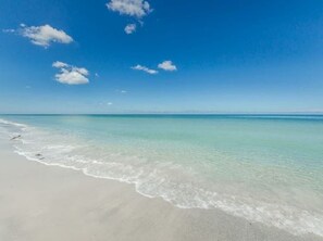 Ein Strand mit klarem türkisblauem Wasser und einem Sandufer.