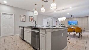 A modern kitchen with a central island, stainless steel appliances, and pendant lighting. - Waterpark, Caribbean Backyard, Epic Game Room w/ Pool Table: Florida Dreamin (Davenport)