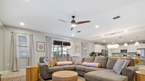 A modern living room with a sectional sofa, ottoman, and a ceiling fan. - Waterpark, Caribbean Backyard, Epic Game Room w/ Pool Table: Florida Dreamin (Davenport)