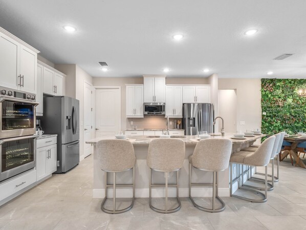 A modern kitchen with white cabinets, stainless steel appliances, and a central island with bar stools.