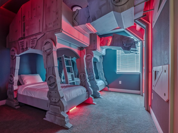 A futuristic bedroom with bunk beds, a ladder, and a window with blinds.