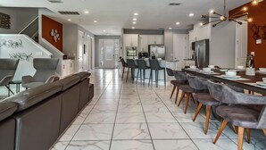 Une cuisine moderne dotée d’un îlot central, de tabourets de bar et d’un coin repas avec une longue table.