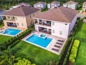 A residential complex with two swimming pools, a covered patio, and a well-maintained lawn.