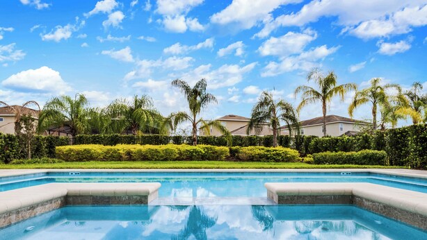 Une piscine à l’eau d’un bleu cristallin, entourée d’une végétation luxuriante et de palmiers bien entretenus.