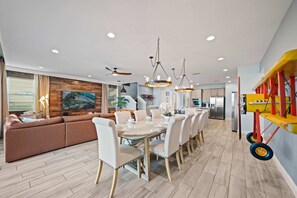 A modern dining area with a long table and chairs, a brown sofa, and a ceiling fan. - Arcades, Mustang Pool Table, As Seen on TV, Massage Chair: The Adventurer (Kissimmee)