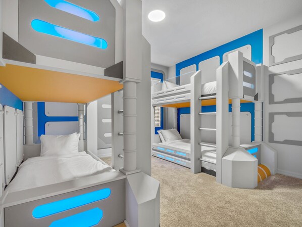 Ein Schlafzimmer mit Etagenbett, modern gestaltet, in Weiß und Blau gehalten, mit Teppichboden.