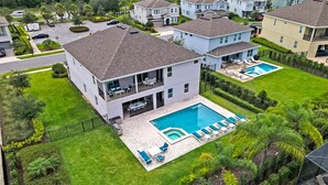Uma casa de dois andares com piscina, varanda e gramado bem cuidado.