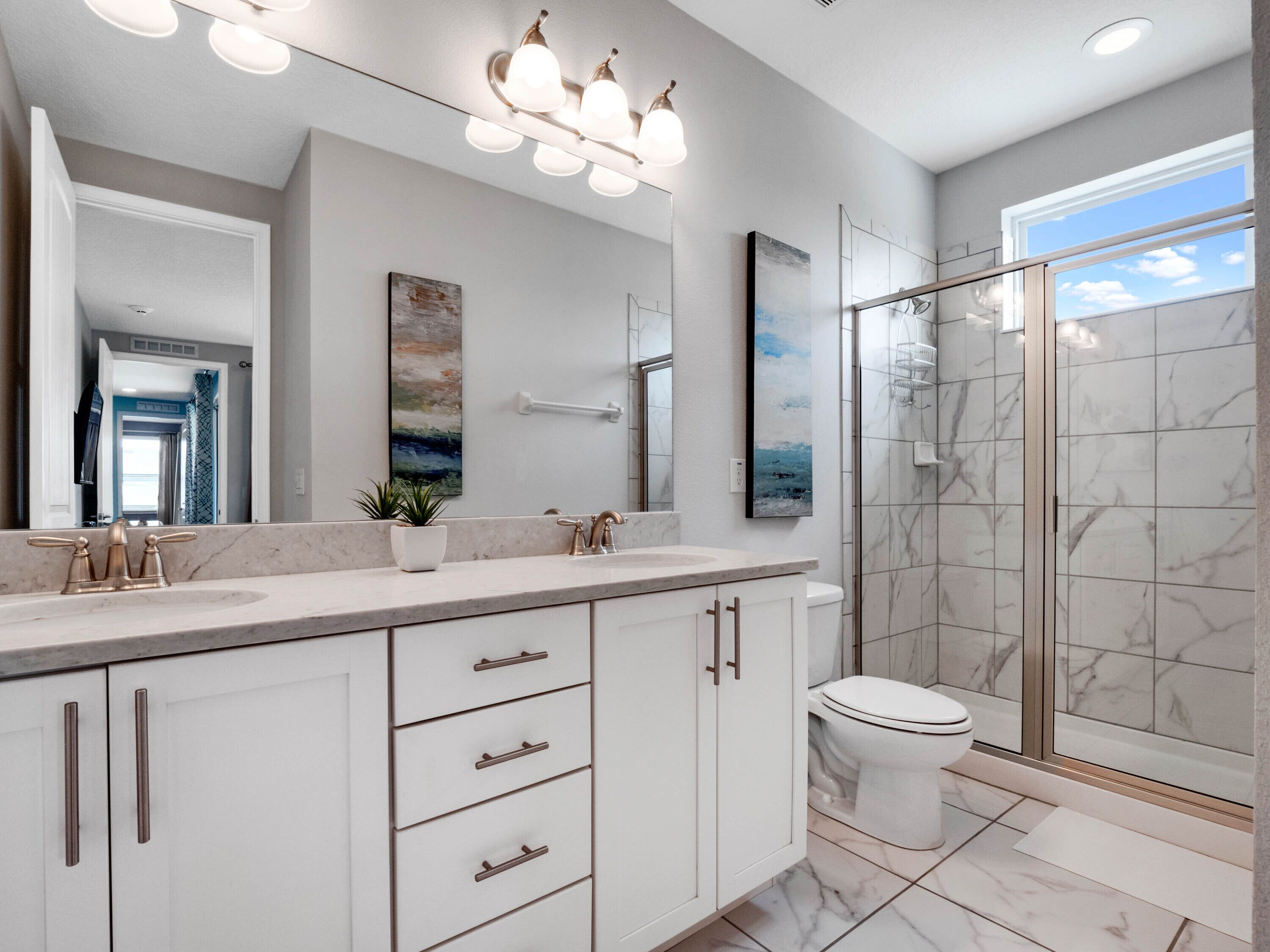 Une salle de bain moderne avec un grand miroir, un meuble-lavabo et un espace douche.