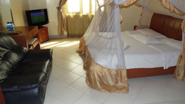 Une chambre avec un lit, une télévision, un fauteuil en cuir et une table de chevet.