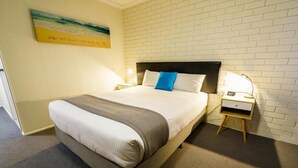 Une chambre d’hôtel avec un lit, une table de chevet, une lampe et un tableau au mur.