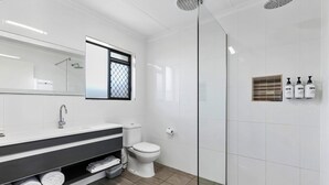 Une salle de bain moderne équipée d’une douche, de toilettes et d’un meuble-lavabo avec des serviettes.