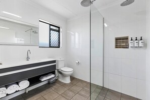 Een moderne badkamer met een douche, toilet en een wastafel met handdoeken.