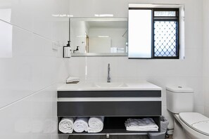 Een moderne badkamer met een wit wastafelmeubel, spiegel en toilet.