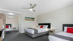 Ein Hotelzimmer mit zwei Betten, einem Deckenventilator, einem Schreibtisch und einem kleinen Tisch.