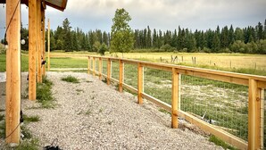 Une structure en bois avec un chemin de gravier menant à un champ clôturé.