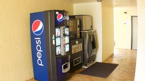 A Pepsi vending machine and a microwave in a hallway with tiled flooring. - At Home Inn (Fort Pierce)