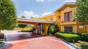 A yellow building with a red door, a sign indicating 9 clearance, and a surveillance sign. - Rodeway Inn and Suites (Little Rock)