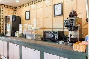 A self-service breakfast area with a microwave, coffee machine, and various food containers. - Rodeway Inn And Suites (Little Rock)