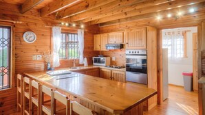 A wooden cabin-style kitchen with a large island, wooden cabinets, a microwave, stove, and a refrigerator. - Lark House, Peaceful Mountain Home with Amazing Ocean Views (Cape Town)