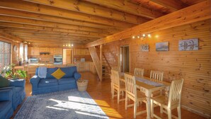 A spacious cabin interior with a wooden dining area, a sofa, and a kitchen. - Lark House, Peaceful Mountain Home with Amazing Ocean Views (Cape Town)