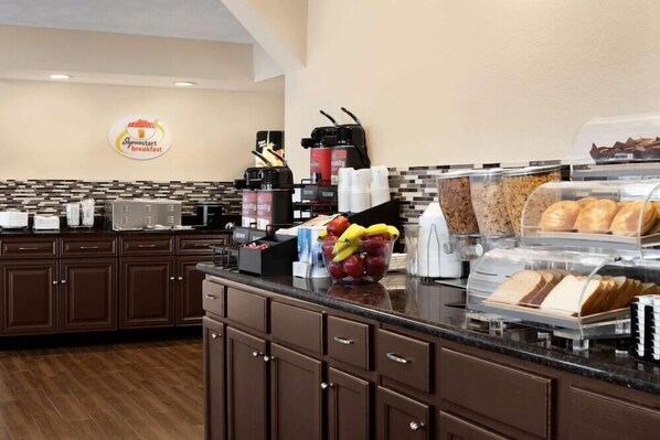 A breakfast area with a coffee machine, fruit bowl, and bread display. - Super 8 By Wyndham Gulfport Near Biloxi (Gulfport)