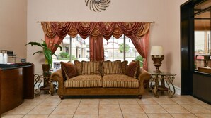 Un salon chaleureux avec un canapé marron, un élément décoratif mural et une vue sur l’extérieur grâce à de grandes fenêtres.