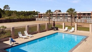 Une piscine avec des chaises longues et un patio clos.
