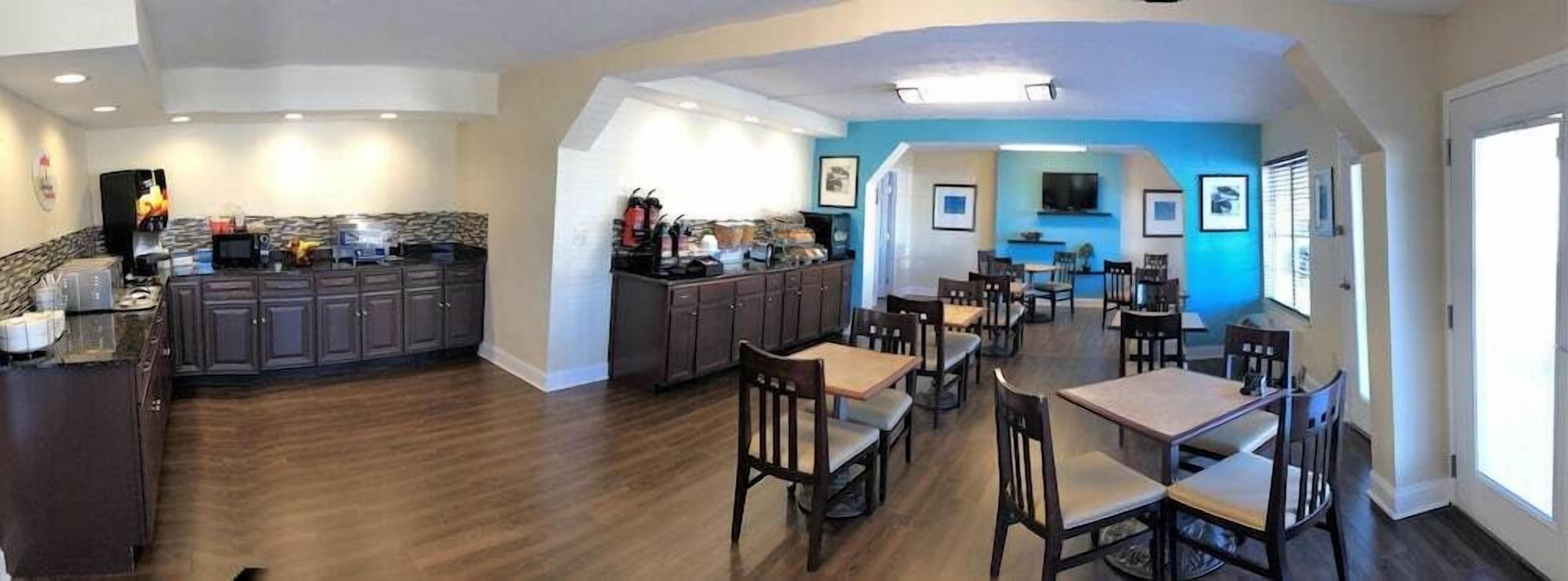 A spacious kitchen with dark wooden cabinets and a dining area with wooden tables and chairs.