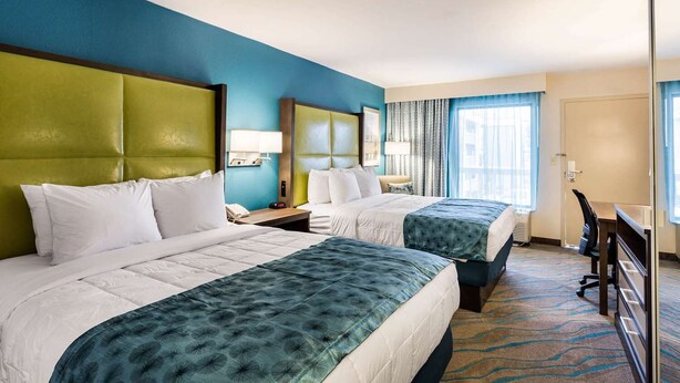 A hotel room with two beds, a desk, and a chair. - Quality Inn Gulfport I-10 (Gulfport)
