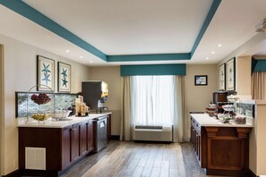 A hotel kitchen with a central island, a coffee station, and a view through a window. - Quality Inn Gulfport I-10 (Gulfport)