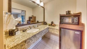 A bathroom with a granite countertop sink, a large mirror, and a microwave above it. - Quality Inn Gulfport I-10 (Gulfport)