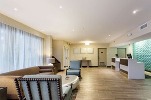 Un vestíbulo de hotel con una recepción, una zona de estar y una escalera.