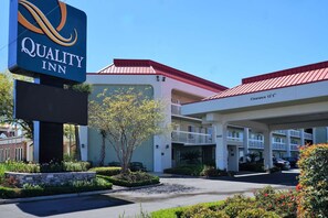 A Quality Inn hotel with a clear sign, a covered parking area, and a well-maintained garden. - Quality Inn Gulfport I-10 (Gulfport)
