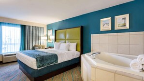 A hotel room with a large bed, a bathtub, and two framed pictures on the wall. - Quality Inn Gulfport I-10 (Gulfport)