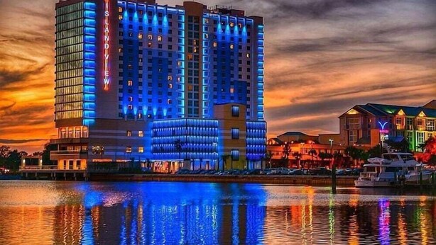 A high-rise hotel with a modern design, featuring a prominent 'Island View' sign, located near a waterfront with reflections visible in the water. - Quality Inn Gulfport I-10 (Gulfport)