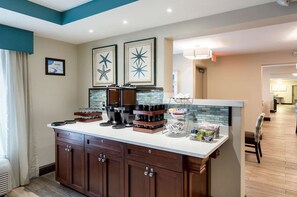 Una cocina con estación de café, zona de comedor y vista al salón.