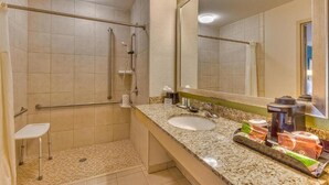 A bathroom with a shower, grab bars, a sink, and a mirror. - Quality Inn Gulfport I-10 (Gulfport)