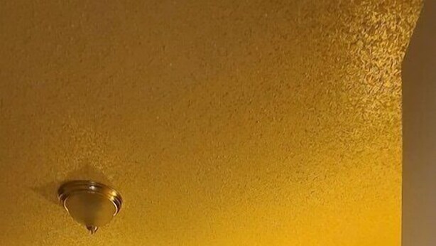 Ein Hotelzimmer mit einem großen Bett, zwei Nachttischlampen, einem dunkel gefärbten Kopfteil und einem gerahmten Bild über dem Bett.