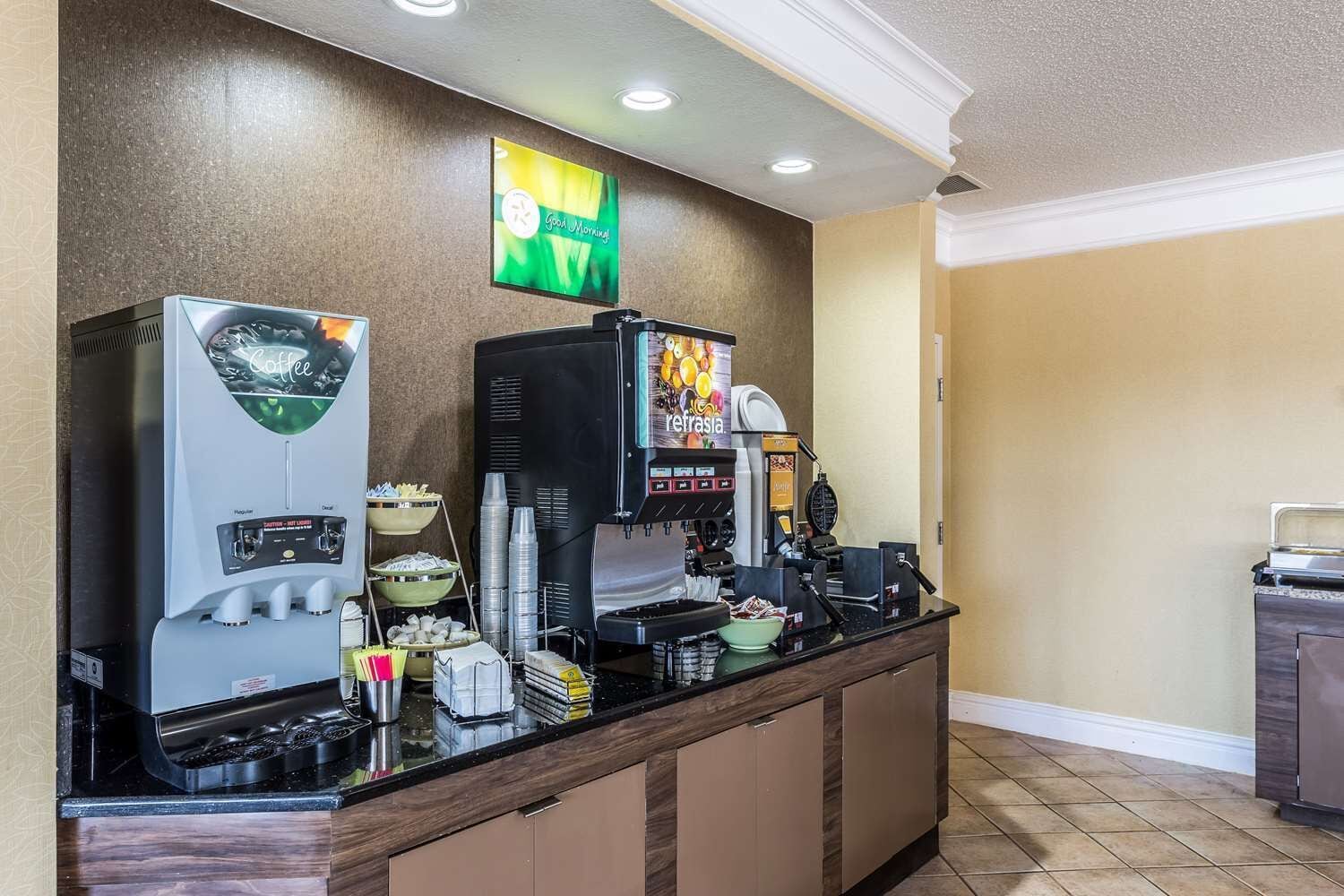 Una estación de café con varias máquinas de café, un dispensador de bebidas y una variedad de tazas y recipientes.