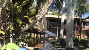 A garden area with a gazebo, outdoor seating, and a building with balconies. - Cozy property just a 3-minute walk from the beach (Free Wifi Room Service) (Buzios)