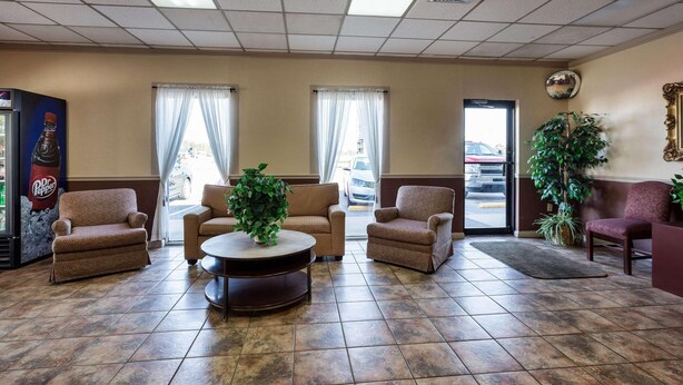 A lobby with four armchairs, a coffee table, and a refrigerator with a beverage dispenser. - Econo Lodge (Osceola)