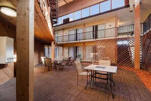 A multi-level atrium with wooden flooring, a dining area with tables and chairs, and a balcony with railings. - Quality Inn Chickasha (Chickasha)