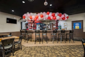 A bar area with a counter, chairs, and a television screen. - Quality Inn Chickasha (Chickasha)